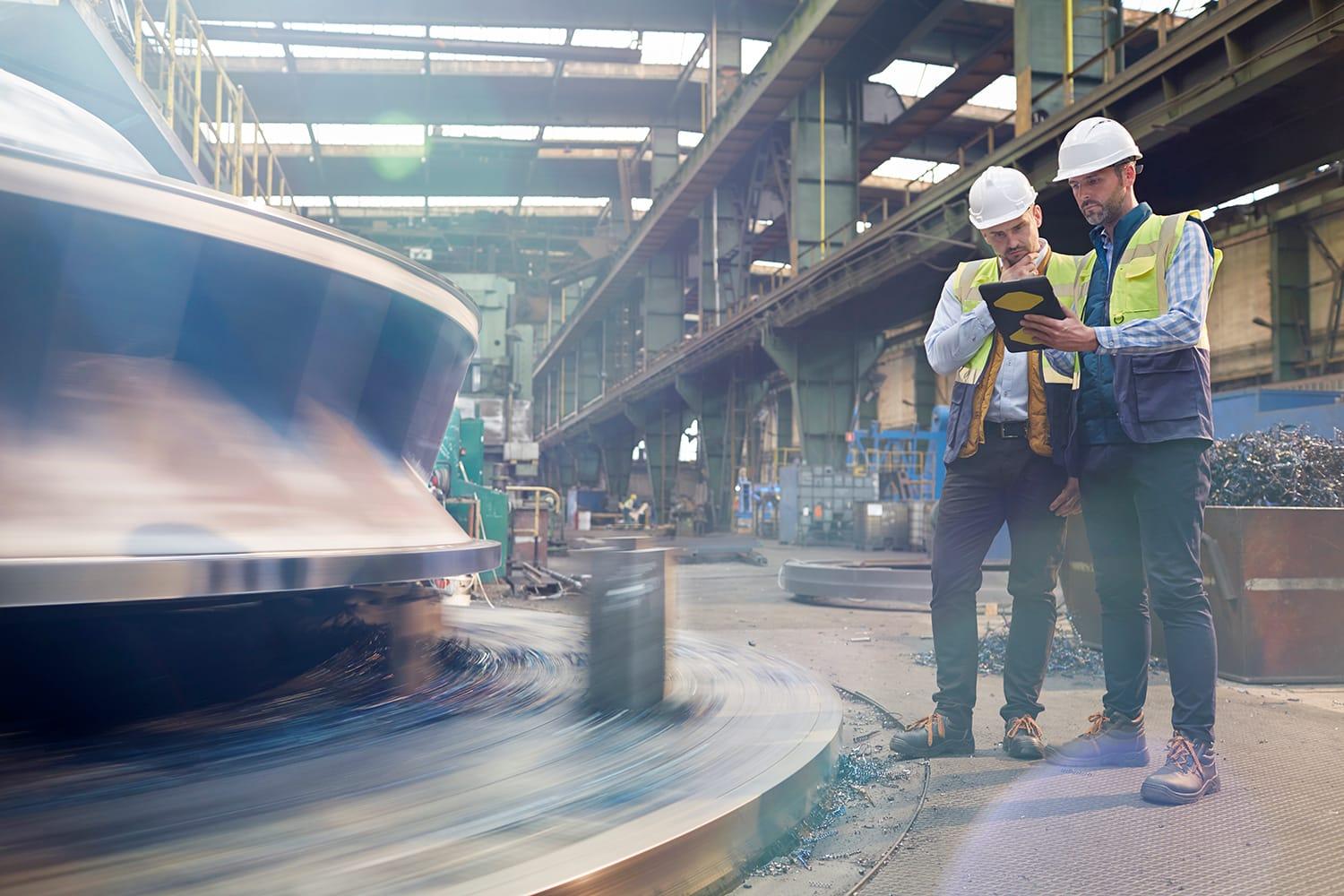 Two workers on factory floor with tablet device Two workers on factory floor with tablet device